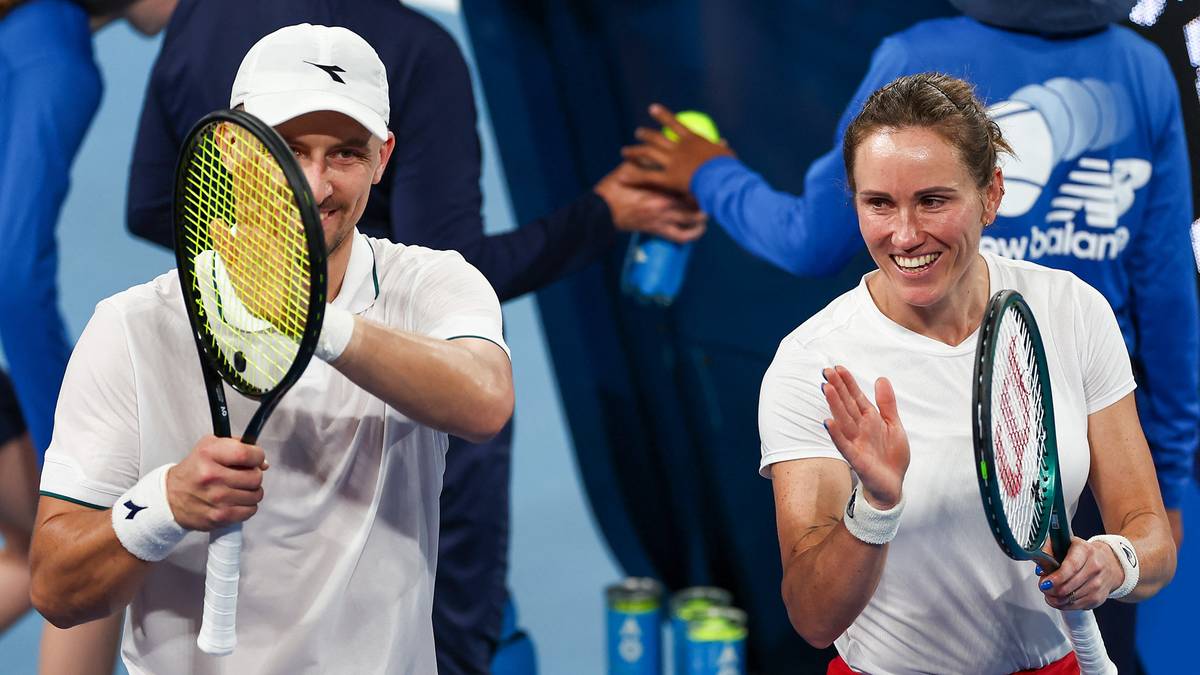 Tenisista z rakietą i uśmiechem na twarzy, obok niego tenisistka z rakietą, oboje radośnie patrzą w stronę obiektywu.