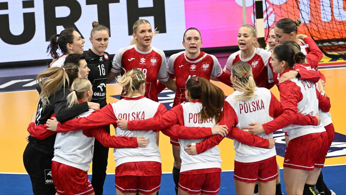 Drużyna piłkarki ręcznej Polski w czerwonych strojach świętuje zwycięstwo, stojąc w kręgu i przytulając się.