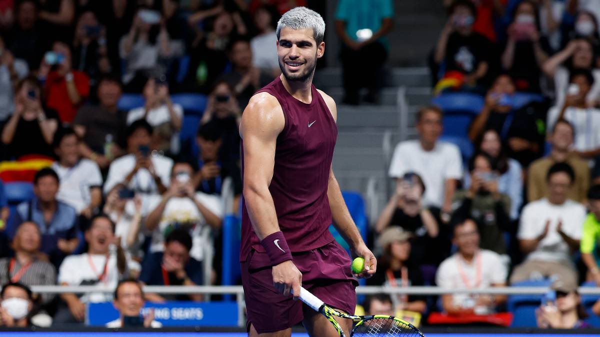 Carlos Alcaraz, tenisista, w stroju sportowym, z rakietą tenisową w ręku, na tle publiczności.