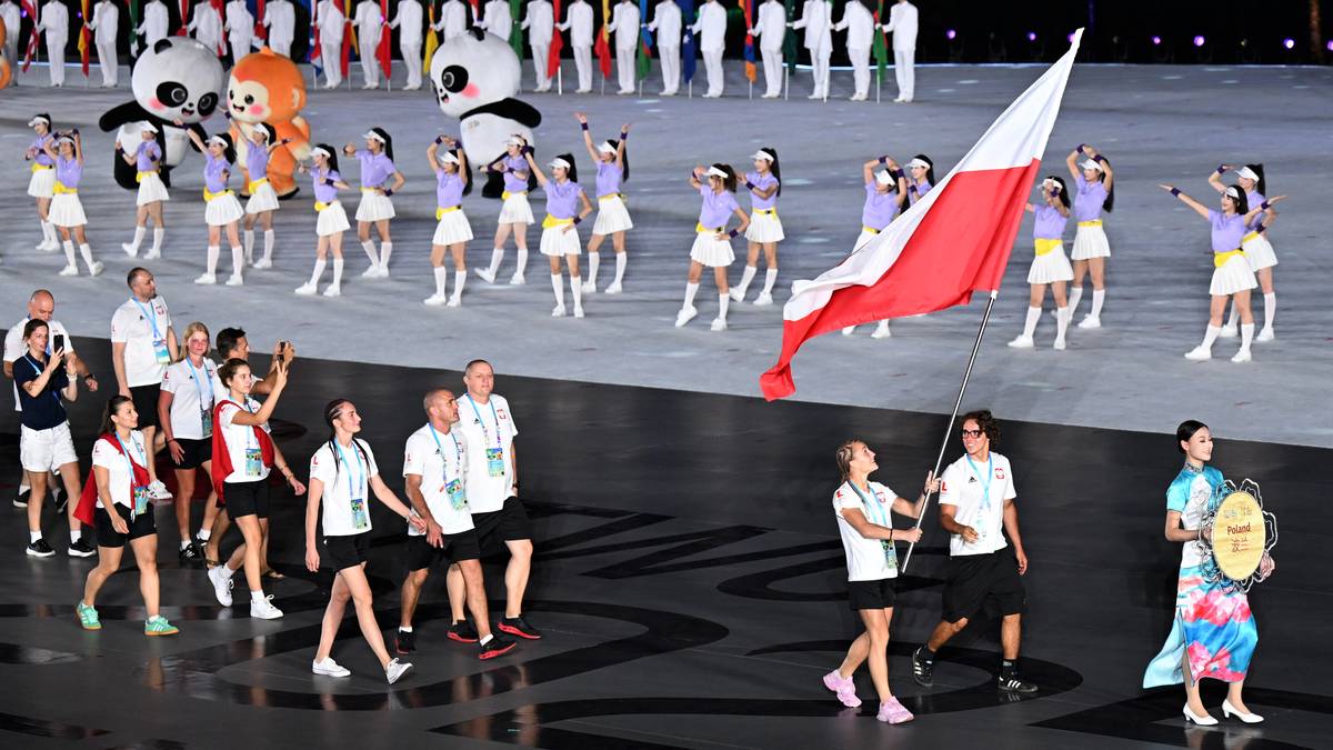 Flaga Polski niesiona podczas ceremonii otwarcia The World Games 2025. W tle grupa osób w strojach reprezentacyjnych oraz maskotki igrzysk.
