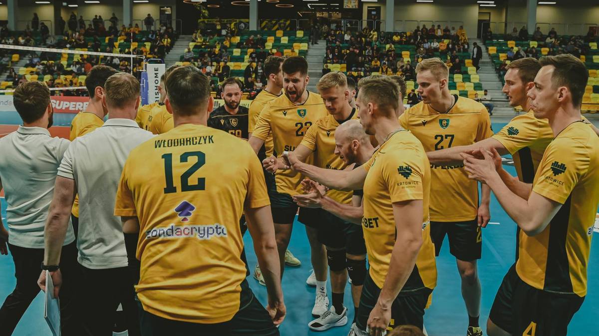 Siatkarze GKS Katowice w ż&oacute;łtych strojach świętują zwycięstwo na boisku, zebrani w grupie.
