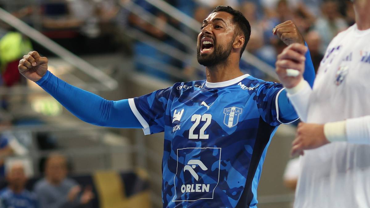 Piłkarz ręczny w niebieskiej koszulce z numerem 22, ORLEN Wisła Płock, świętuje zdobycie bramki, zaciśnięte pięści, wyraźna radość na twarzy, na tle publiczności na trybunach.