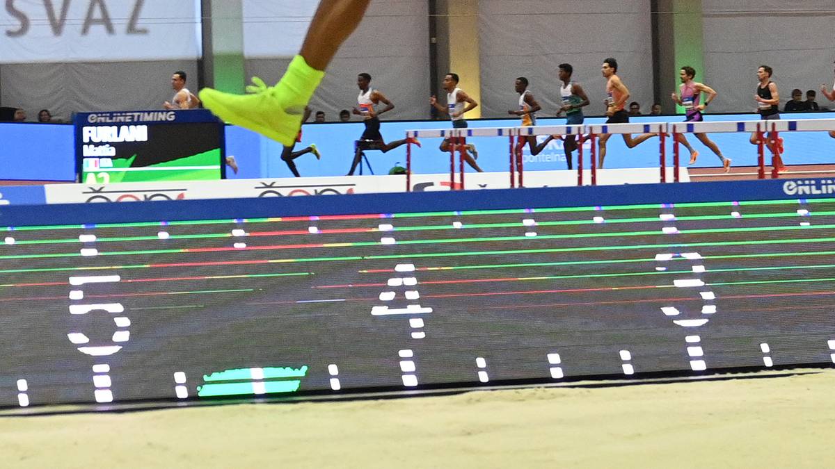 Lekkoatleta w akcji podczas skoku w dal w hali sportowej.