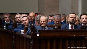 Grupa mężczyzn siedzących w ławach w pomieszczeniu przypominającym salę posiedzeń.