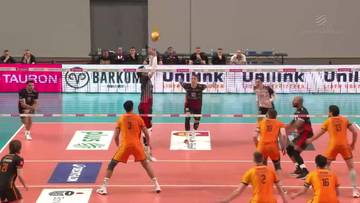 Gracz w pomarańczowym stroju wykonuje zagrywkę w meczu siatk&oacute;wki.