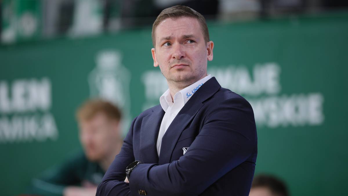 Mężczyzna w garniturze, z założonymi rękami, patrzący przed siebie.