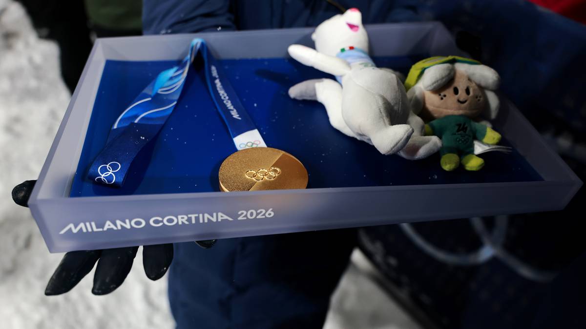 Złoty medal igrzysk Mediolan-Cortina 2026 na tacce z maskotkami i pucharem.