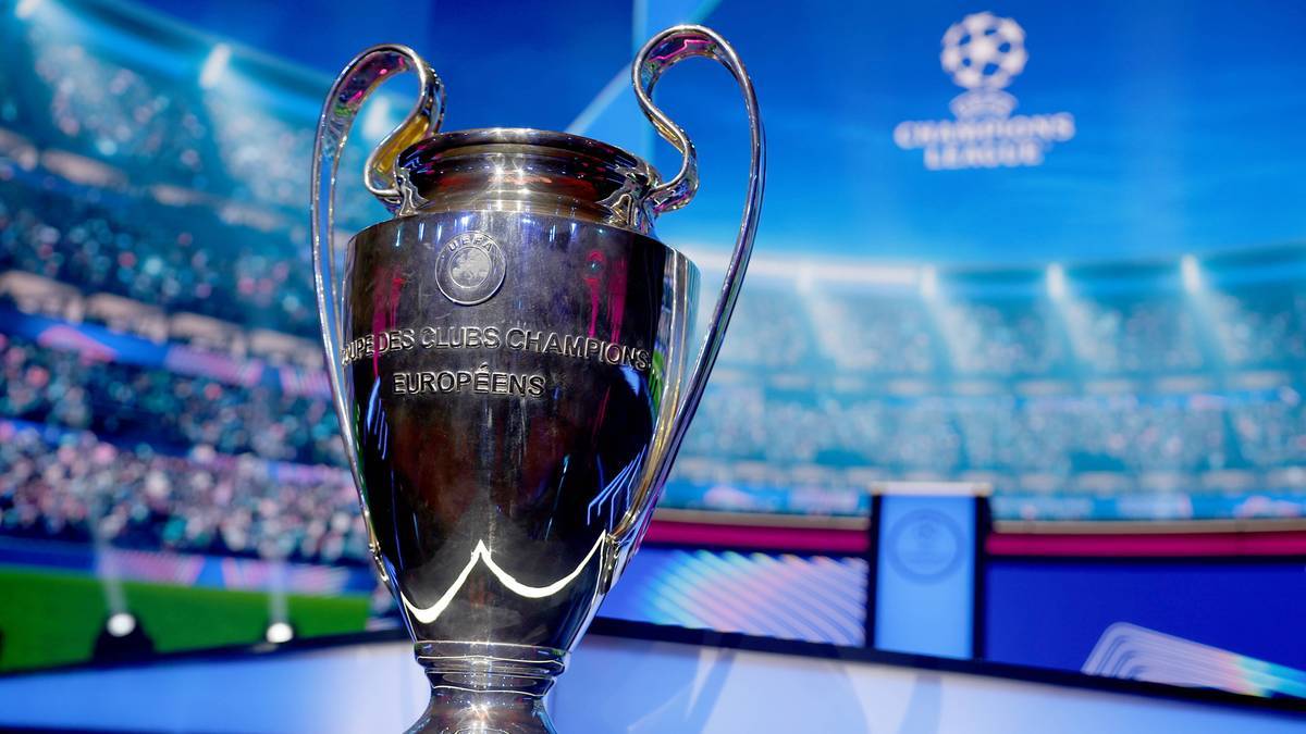Trofeum Ligi Mistrz&oacute;w UEFA na tle stadionu i logo rozgrywek.