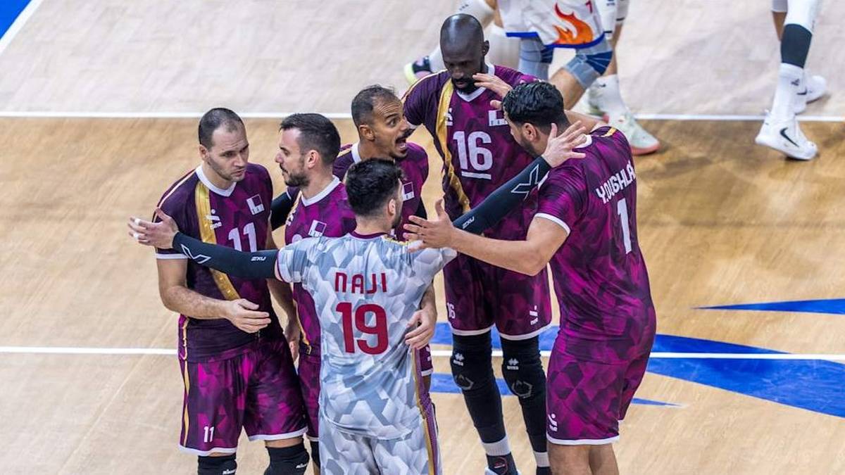 Drużyna siatkarzy w bordowych strojach świętuje zwycięstwo, obejmując się i ciesząc na boisku.