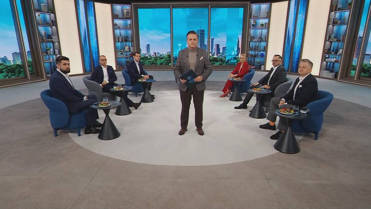 Prezenter w studio telewizyjnym prowadzi program publicystyczny w otoczeniu siedzących gości