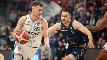 Koszykarz prowadzący piłkę podczas meczu, broniony przez przeciwnika.