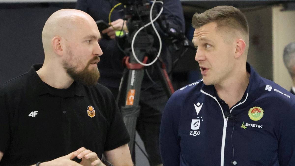 Dw&oacute;ch mężczyzn w strojach sportowych rozmawia ze sobą, jeden w czarnej koszulce, drugi w granatowej kurtce.