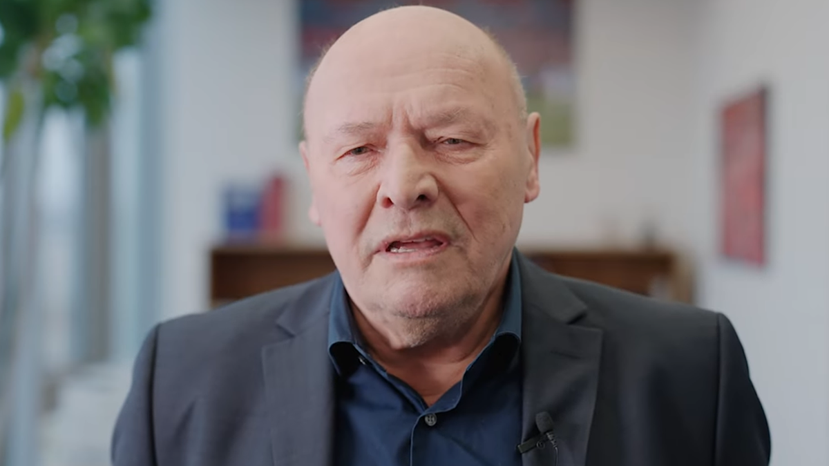 Portret starszego mężczyzny w garniturze i koszuli, m&oacute;wiącego.