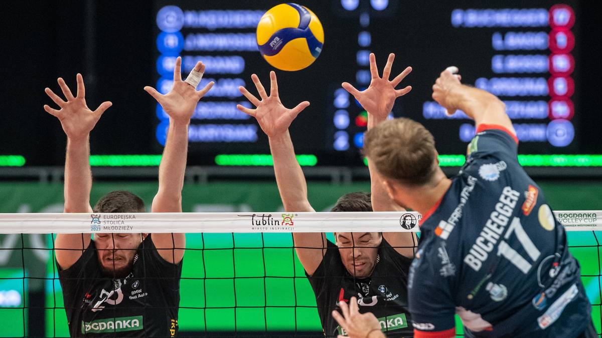 Siatkarze w akcji podczas meczu, piłka w powietrzu, blokujący gracze.