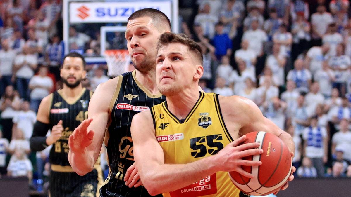 Dw&oacute;ch koszykarzy w trakcie meczu, jeden w ż&oacute;łtej koszulce z numerem 55 prowadzi piłkę, drugi w czarnej pr&oacute;buje go zatrzymać.