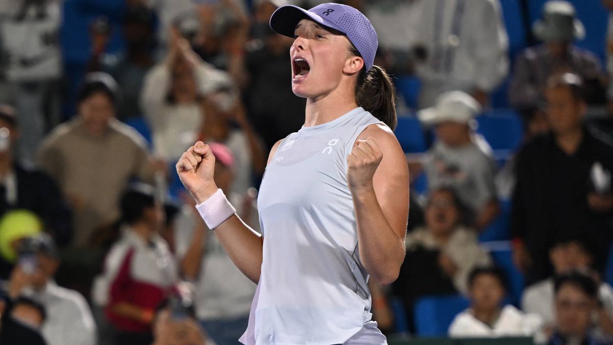 Iga Świątek, tenisistka, świętuje zwycięstwo na korcie, wznosząc ręce w górę i krzycząc z radości.