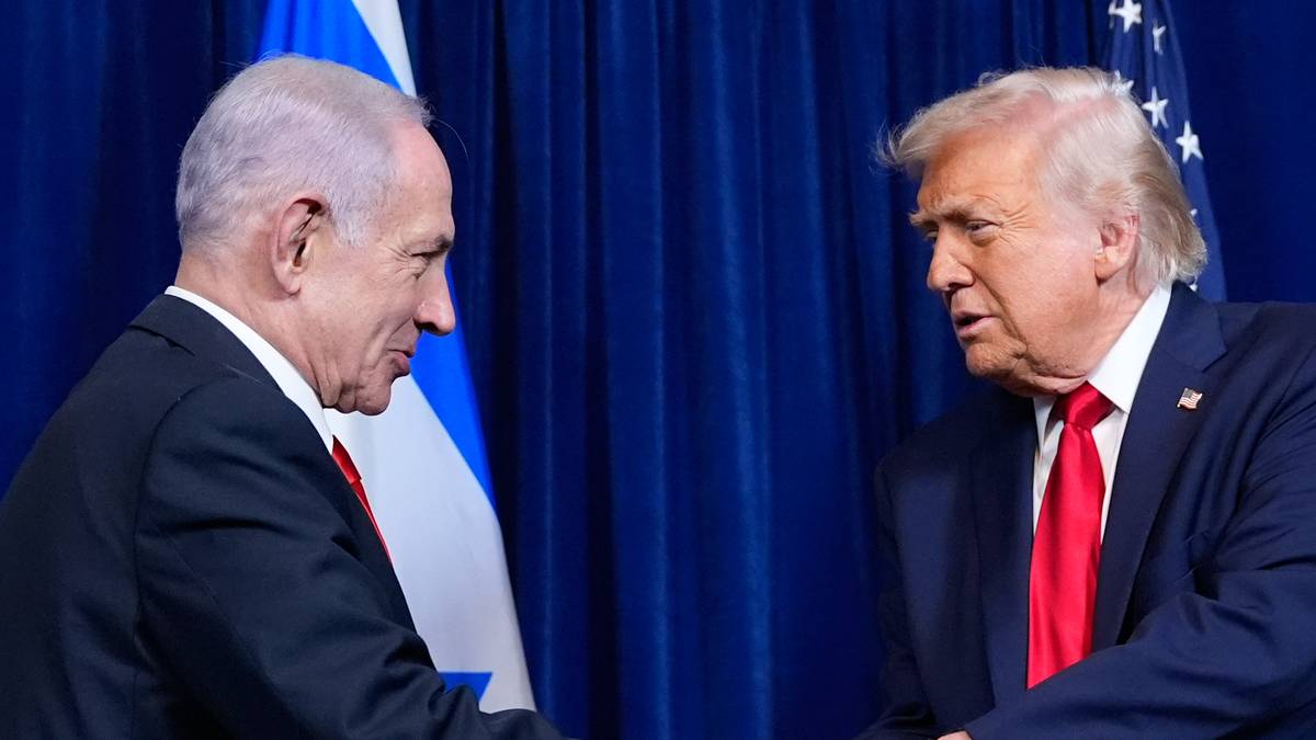 Benjamin Netanjahu i Donald Trump ściskają sobie dłonie na tle flag Izraela i USA.