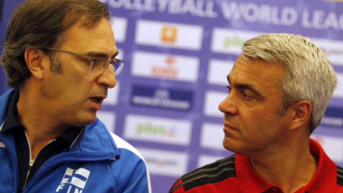 Dw&oacute;ch trener&oacute;w siatk&oacute;wki rozmawia na tle ściany z logo Volleyball World League.