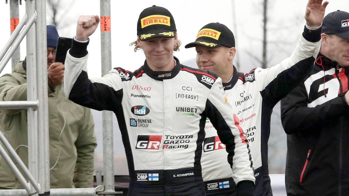 Dwóch kierowców w kombinezonach rajdowych z logiem GR Toyota Racing, z uniesionymi pięściami w geście radości, noszą czapki z daszkiem.