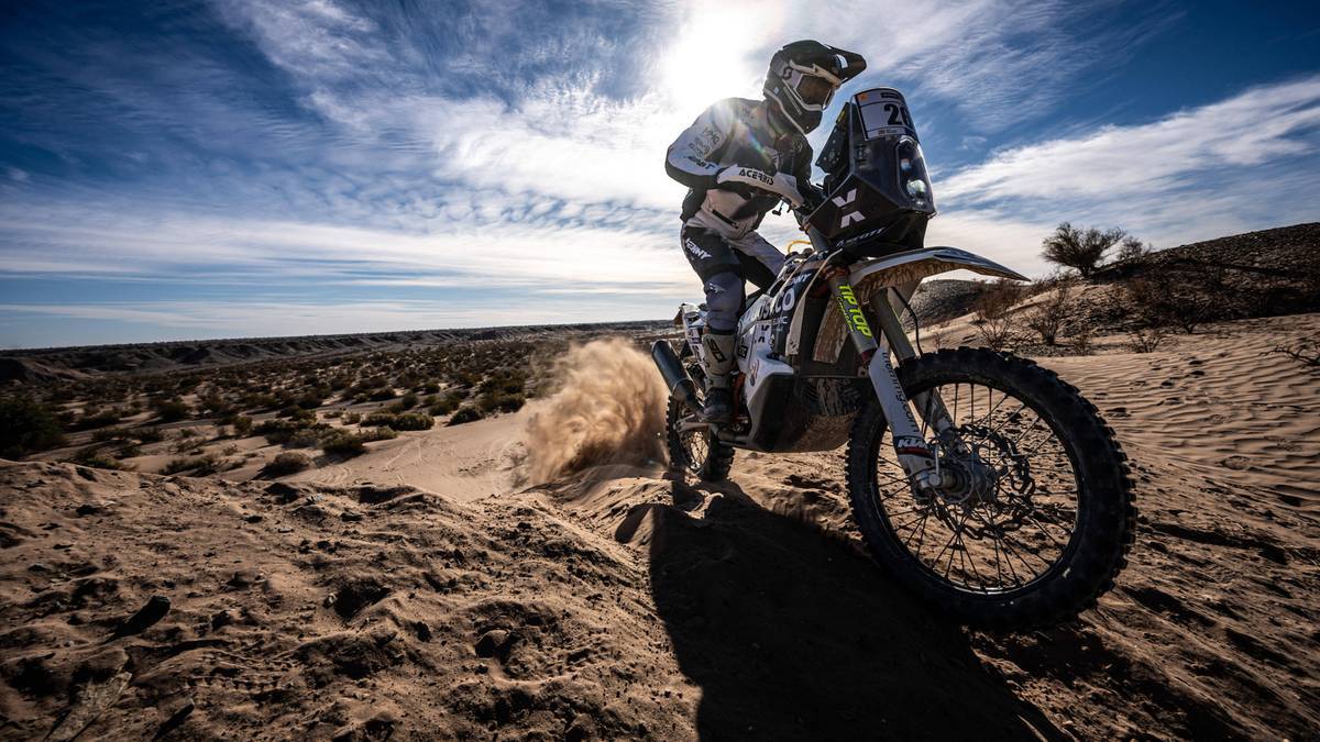 Motocyklista ścigający się po pustynnym terenie.