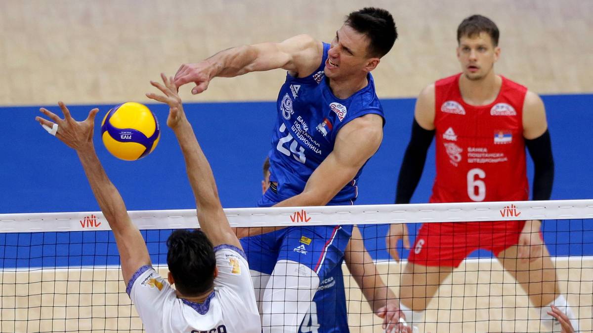 Siatkarze w akcji podczas meczu siatkówki, jeden z nich blokuje atak przeciwnika.