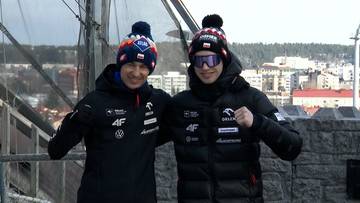 Dw&oacute;ch skoczk&oacute;w narciarskich w zimowych czapkach i kurtkach pozuje do zdjęcia, uśmiechając się do kamery.