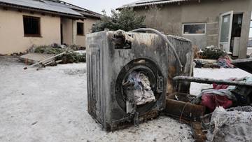 Spalona pralka na zniszczonej posesji po pożarze.