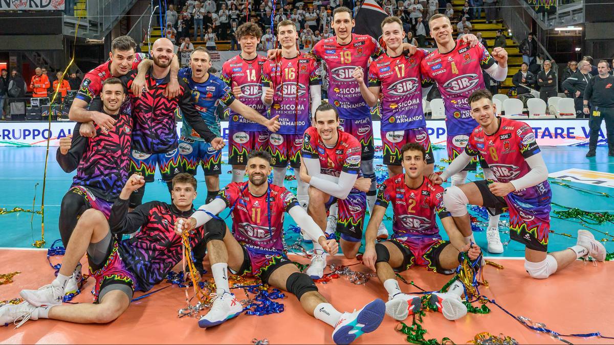 Drużyna siatkarzy w czerwonych strojach pozuje do zdjęcia na parkiecie po meczu.