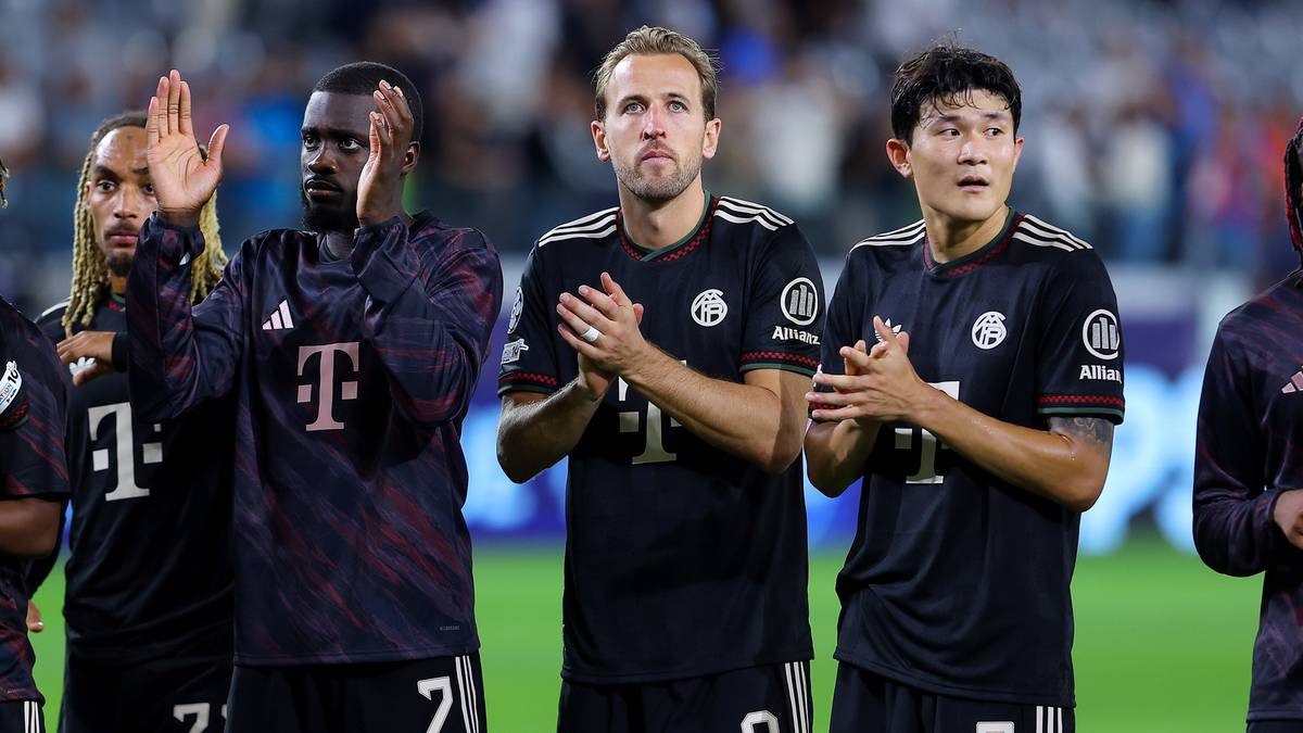 Trzech piłkarzy w czarnych strojach sportowych patrzy przed siebie.