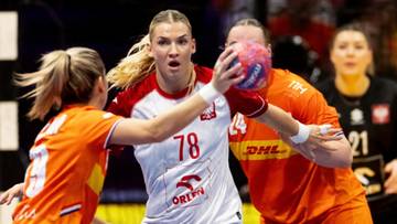 Piłkarka ręczna w białej koszulce z numerem 78 pr&oacute;buje rzucić piłkę, otoczona przez dwie zawodniczki w pomarańczowych strojach.