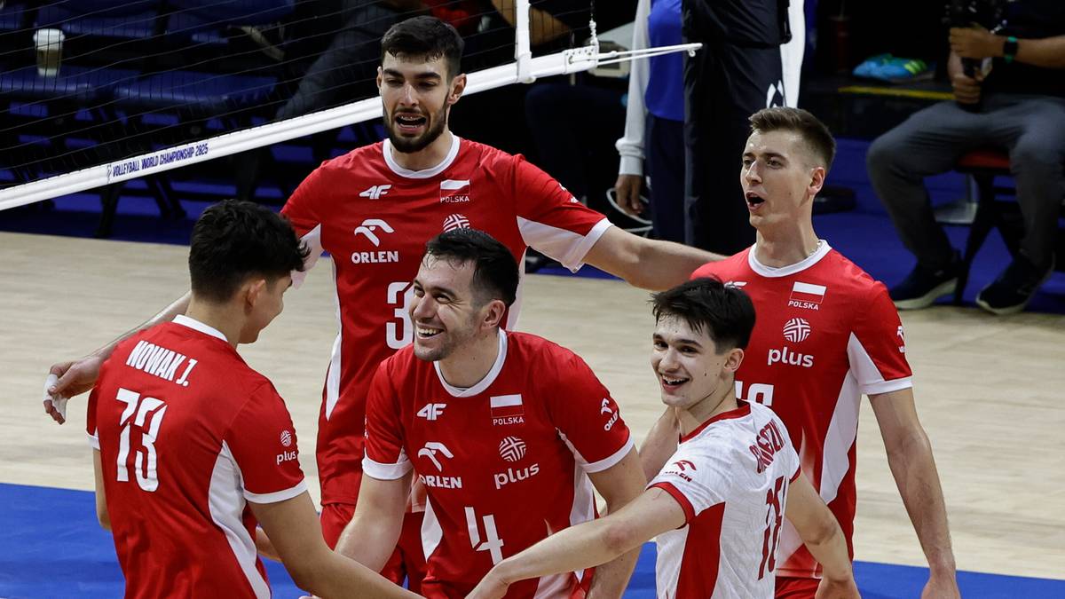 Grupa polskich siatkarzy w czerwonych strojach podczas meczu, świętująca zdobycie punktu.