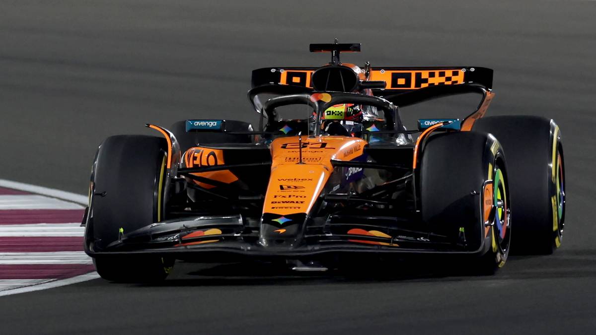 Bolid Formuły 1 zespołu McLaren w kolorach pomarańczowo-czarnym podczas wyścigu na torze.