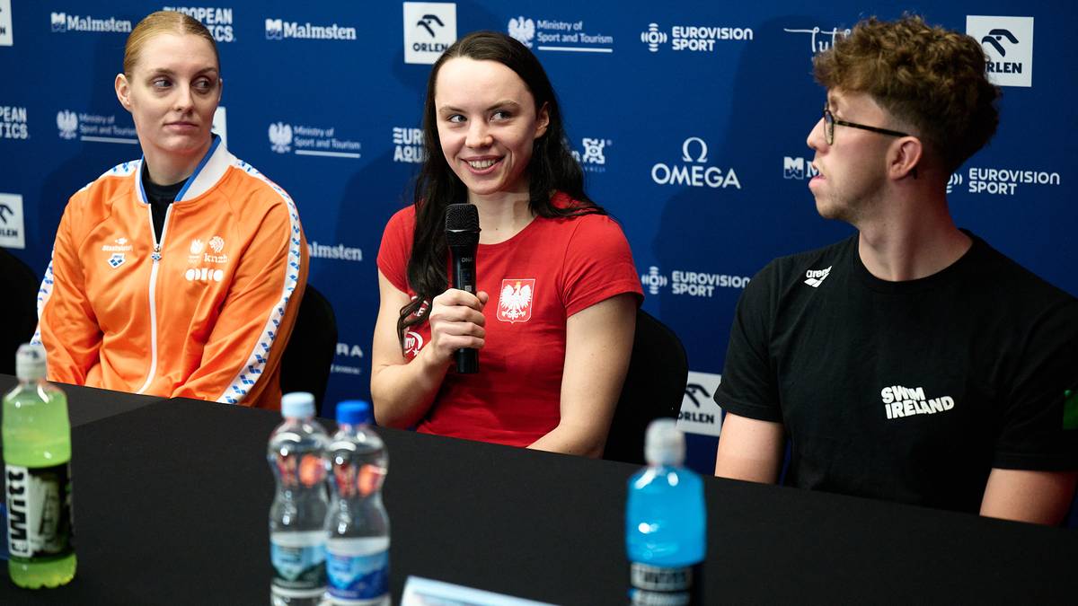 Trzech młodych polskich pływaków siedzących przy stole podczas konferencji prasowej.