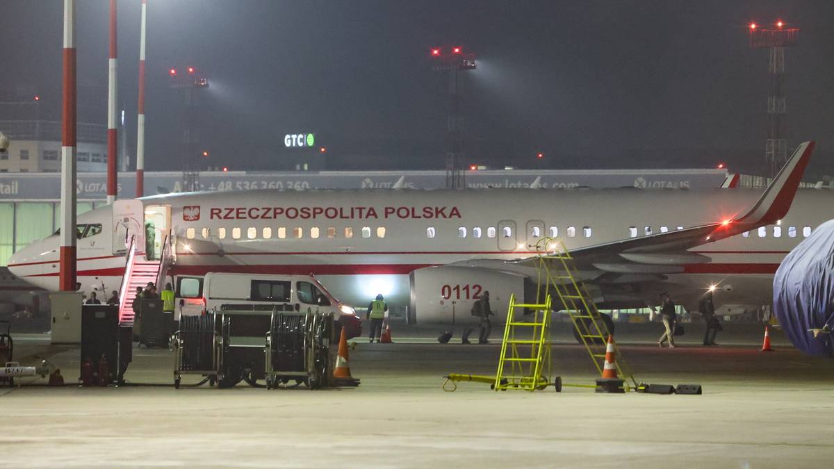 Samolot pasażerski z napisem "RZECZPOSPOLITA POLSKA" na kadłubie, zaparkowany na lotnisku w nocy. Widoczne schody prowadzące do drzwi samolotu, pojazdy obsługi lotniskowej oraz drabina.