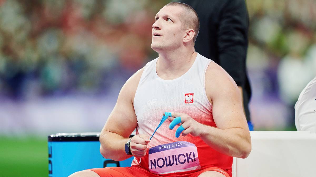 Paweł Nowicki, polski lekkoatleta, siedzi na ławce, trzymając niebieski chwytak w rękach.