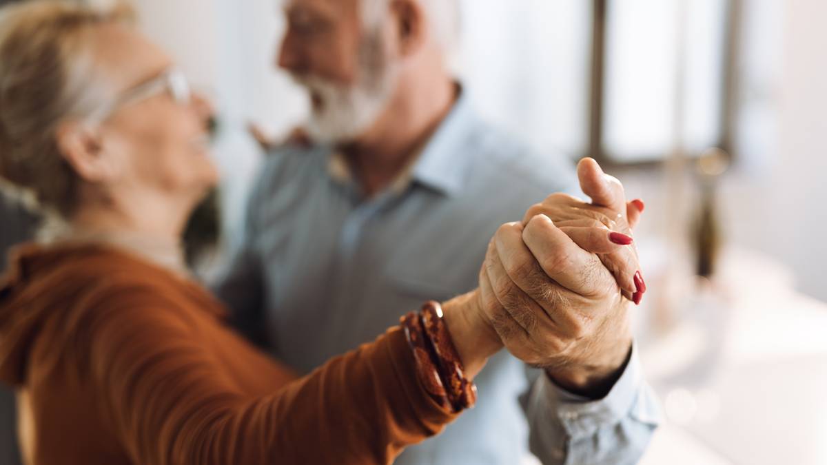 Para seniorów trzymająca się za ręce i tańcząca.