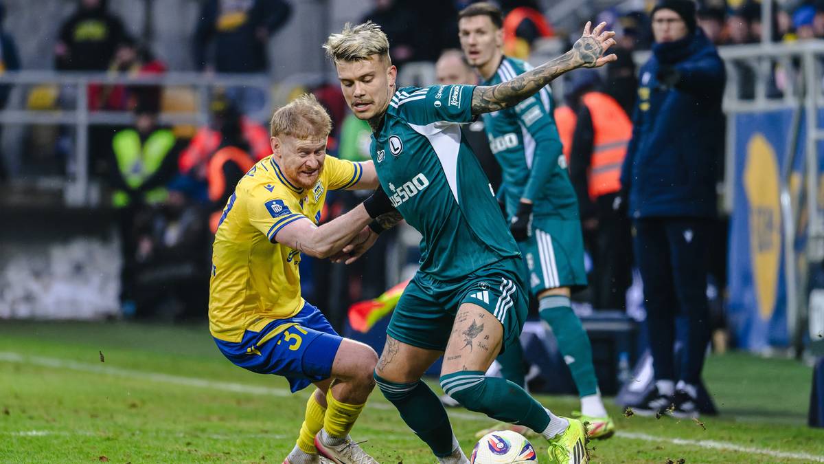 Dw&oacute;ch piłkarzy walczy o piłkę na boisku podczas meczu.