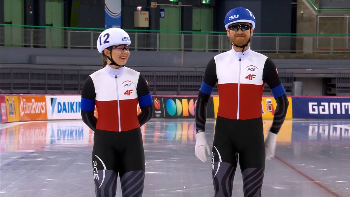Dwóch łyżwiarzy szybkich w strojach reprezentacji Polski stoi na lodowisku.