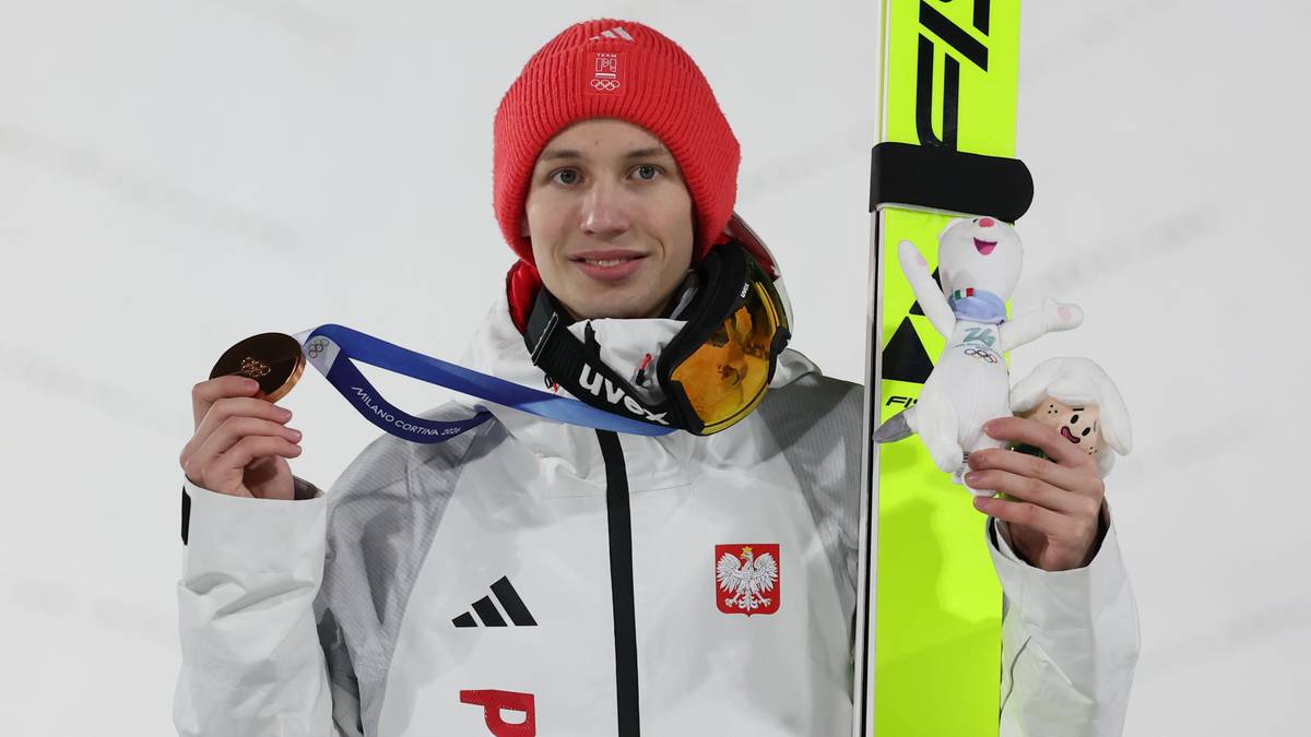 Kacper Tomasiak w stroju narciarskim z dwoma medalami olimpijskimi.