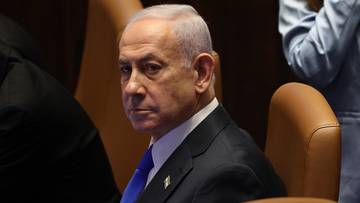 Premier Izraela Benjamin Netanjahu w garniturze siedzi podczas posiedzenia.