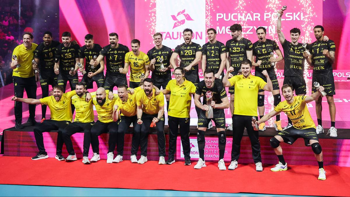 Drużyna siatkarzy w ż&oacute;łtych i czarnych strojach pozuje do zdjęcia na tle sceny z napisem "Puchar Polski".