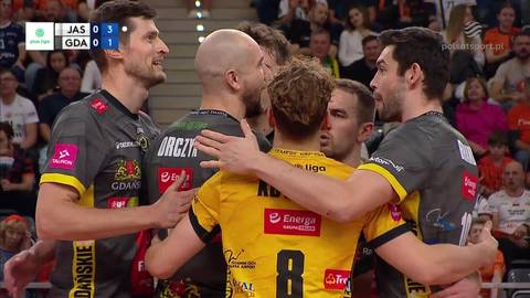 Sześciu siatkarzy w strojach sportowych przytulających się na boisku podczas meczu.