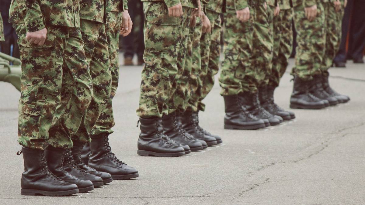 Ujęcie z dołu na nogi żołnierzy w mundurach polowych i czarnych butach wojskowych stojących w szeregu.