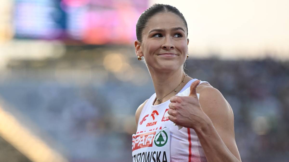 Portret lekkoatletki w białej koszulce sportowej, pokazującej kciuk w górę i uśmiechającej się.