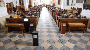 Wnętrze kościoła z wiernymi siedzącymi w ławkach.