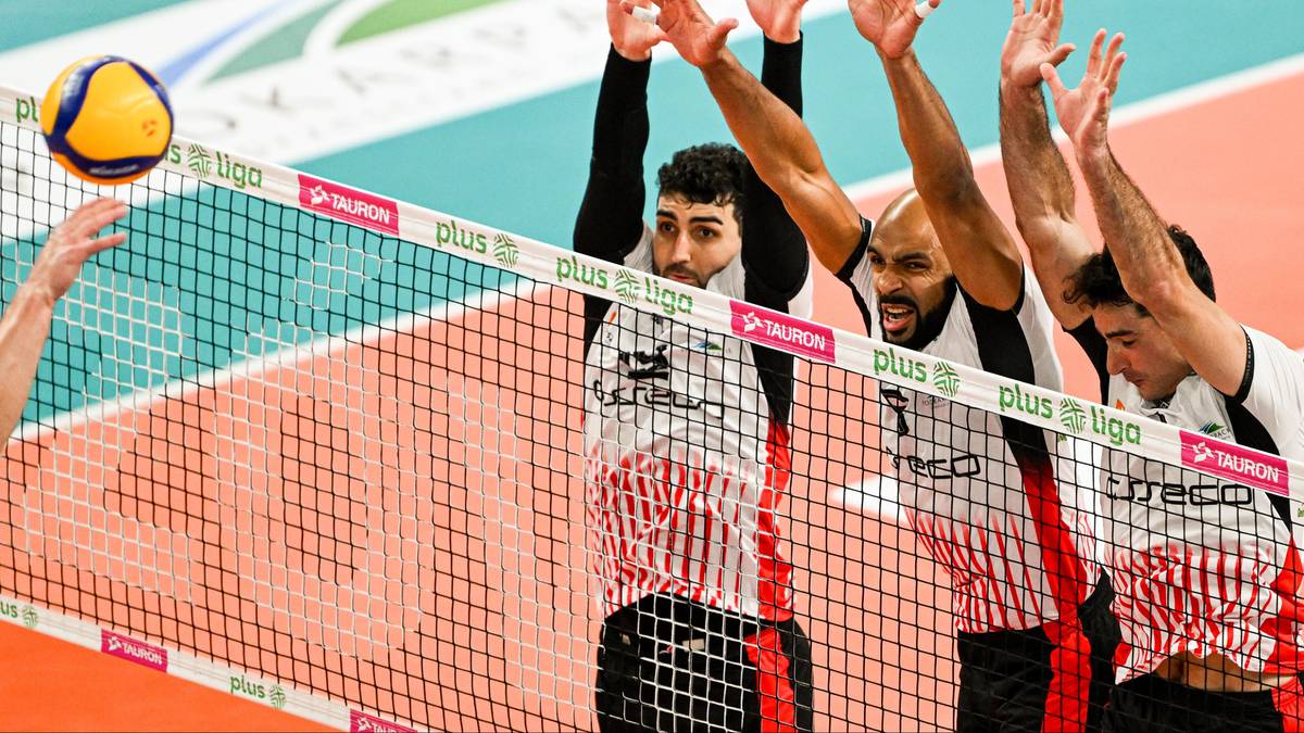 Siatkarze próbują zablokować piłkę nad siatką.