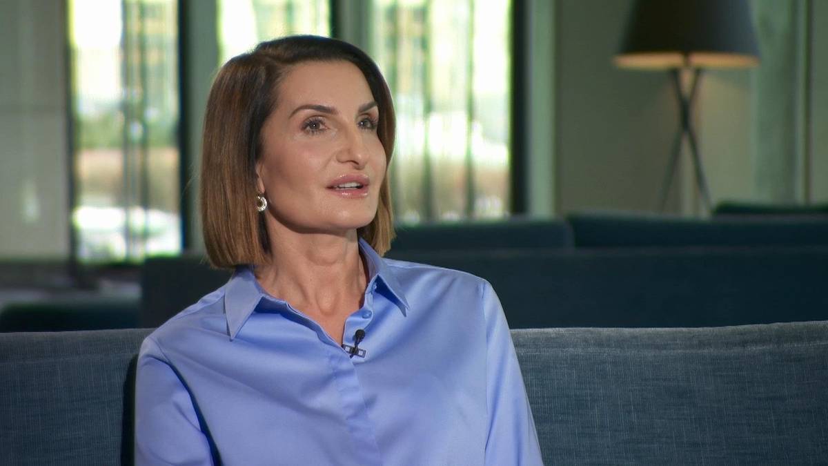 Kobieta w niebieskiej koszuli siedzi na kanapie.