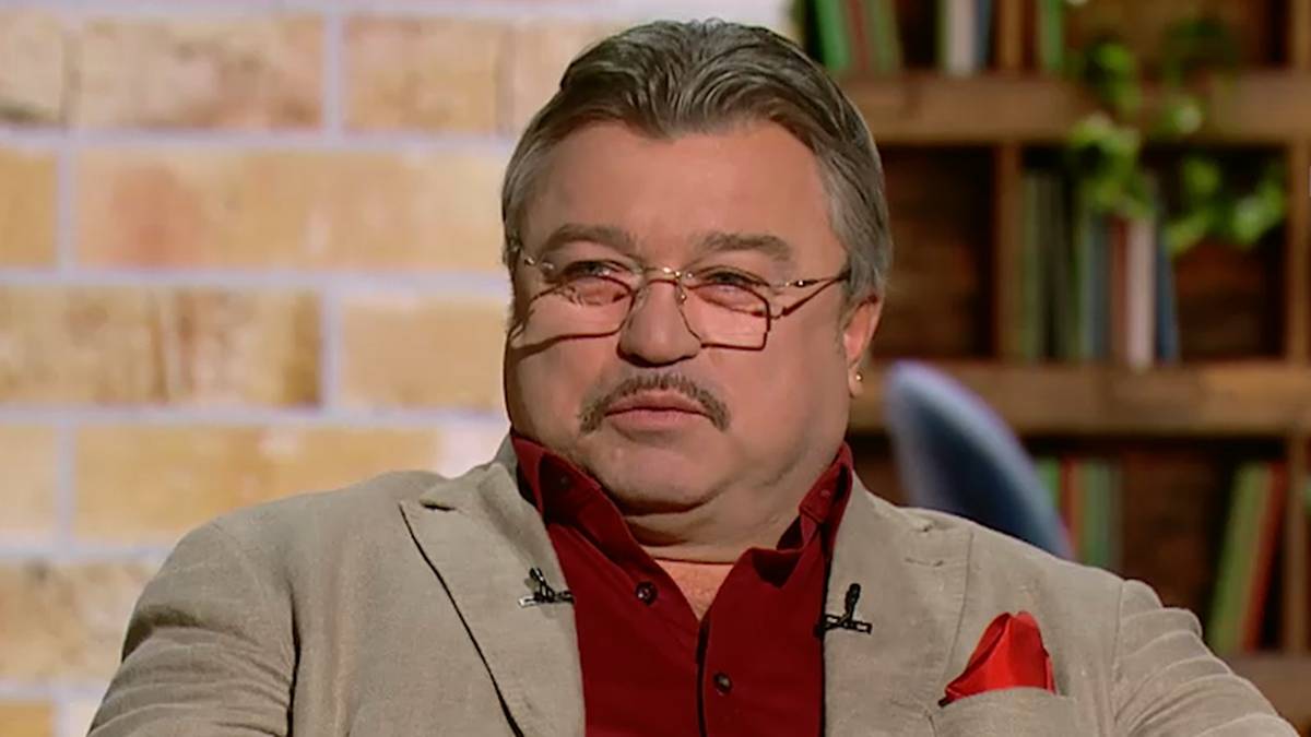 Mężczyzna w okularach siedzi na kanapie w studiu telewizyjnym