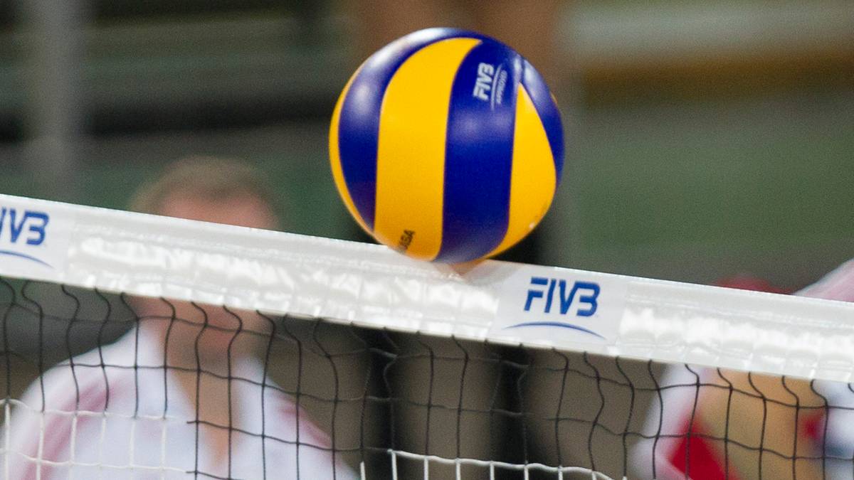 Piłka do siatk&oacute;wki w kolorach niebieskim i ż&oacute;łtym leżąca na siatce.