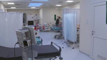 Wnętrze szpitalnego oddziału z ł&oacute;żkami i sprzętem medycznym.